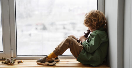 Immagine di un bambino che guarda dalla finestra con vetro trasparente
